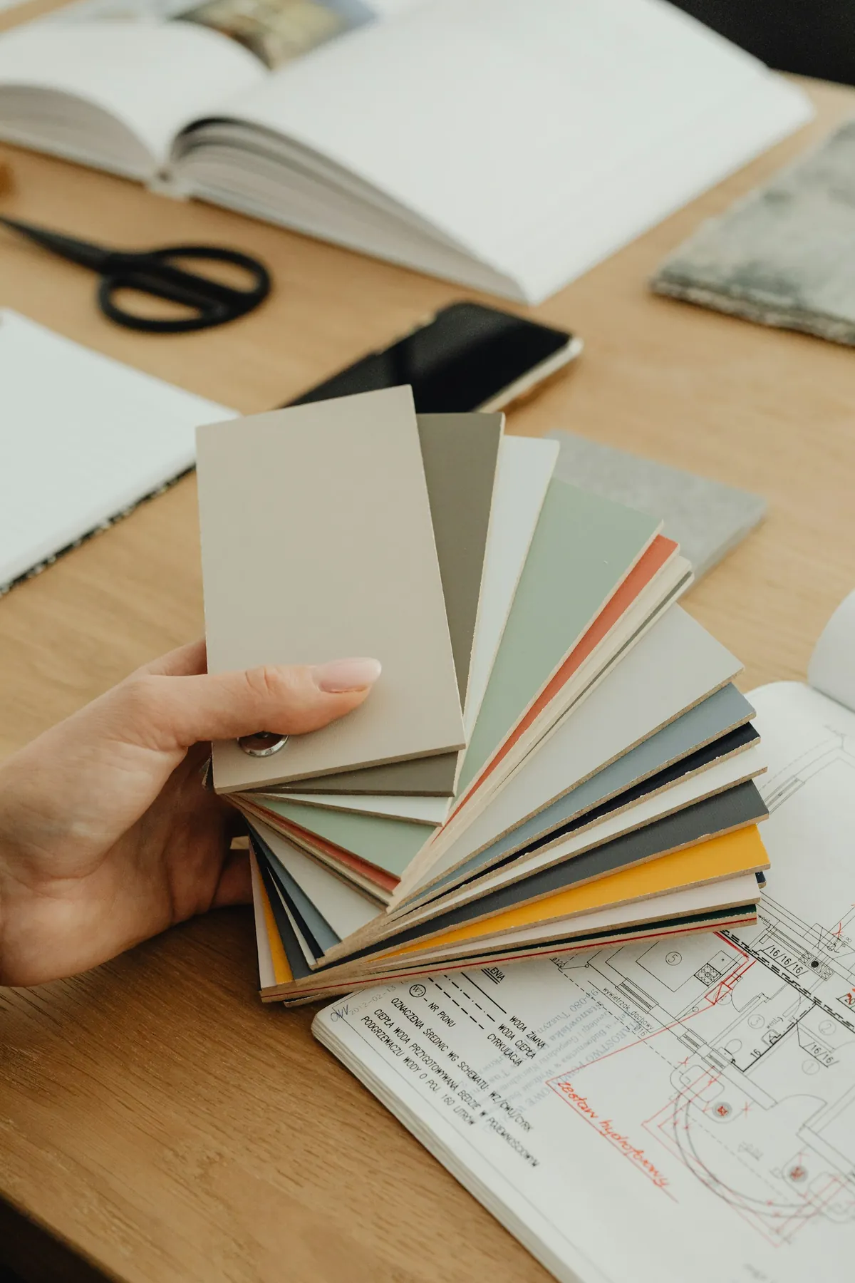 Hand holding a fan of colour samples over house plans