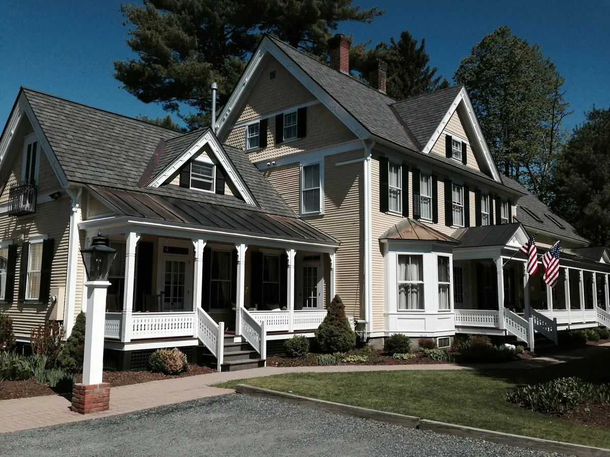 Large shingle-style house with a wraparound porch and gables