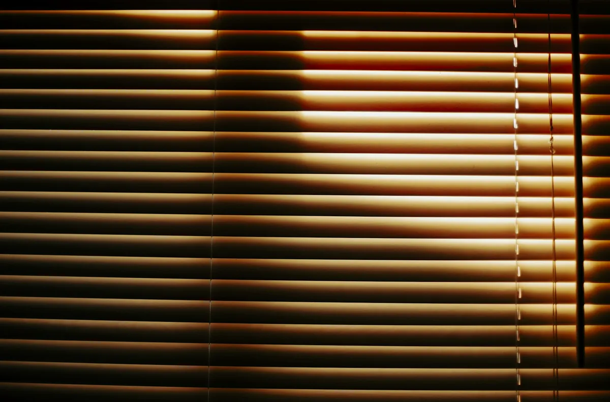 Close view of horizontal blinds glowing with light from behind