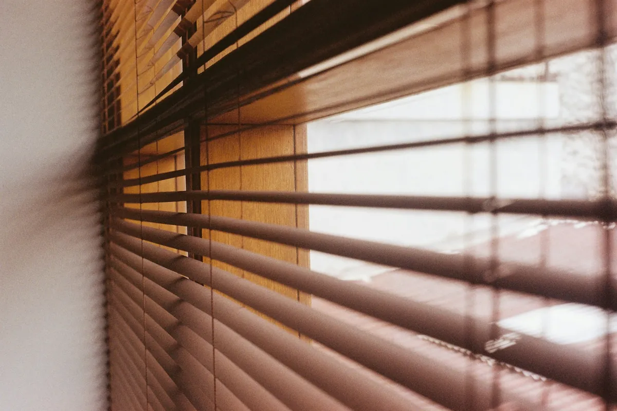 Close view of wood blinds with daylight behind them