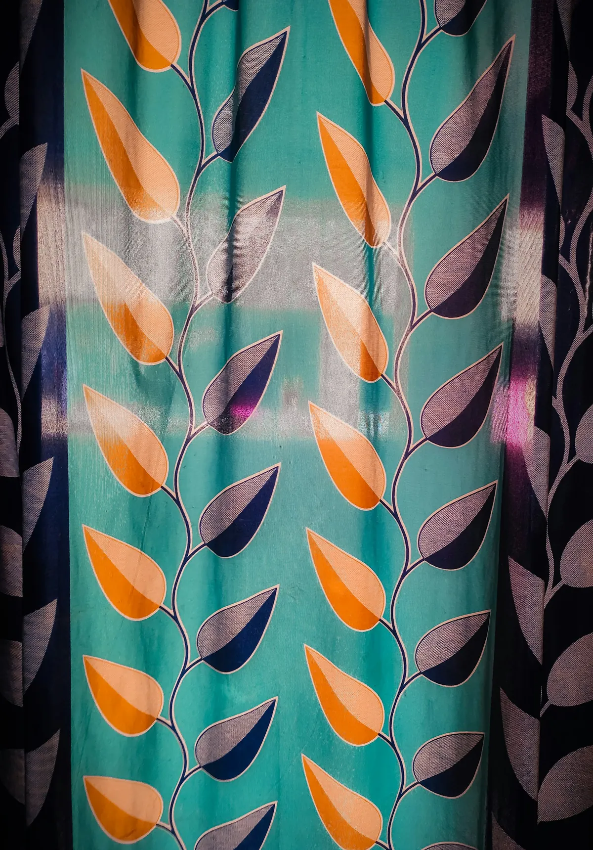 Teal curtain fabric printed with orange and purple leaves