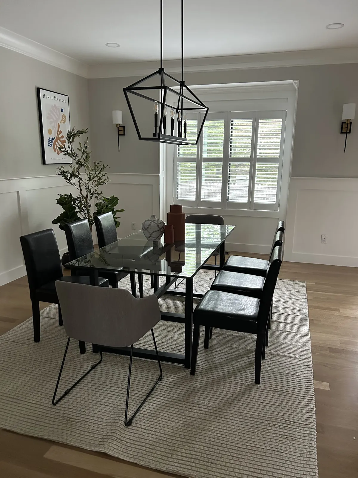 Dining room with white plantation shutters on the windows behind a glass table