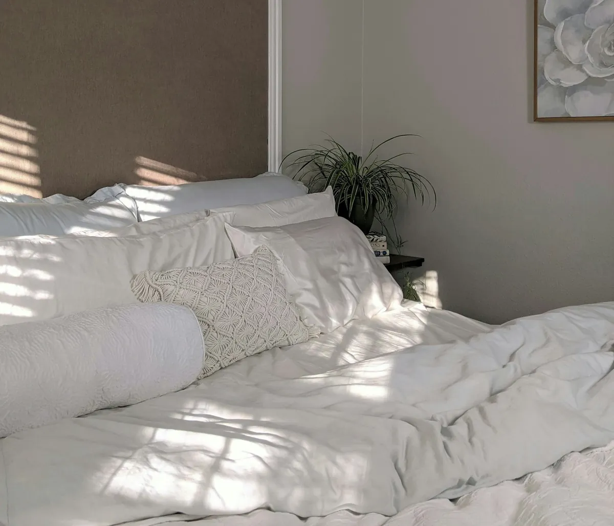 White duvet and pillows on a bed in soft sunlight