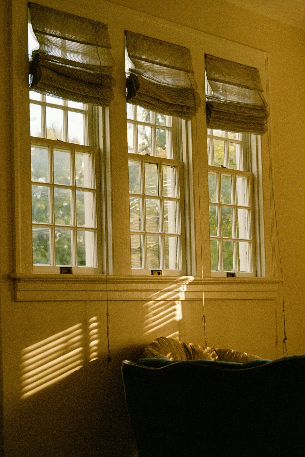 Roman shades on three sash windows in low gold sun