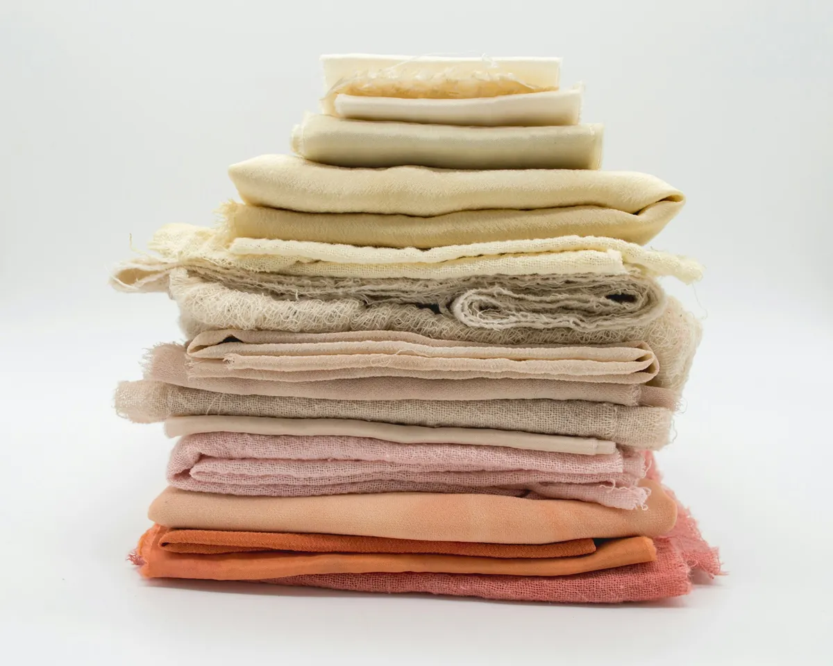 Stack of folded fabrics in creams and soft pinks