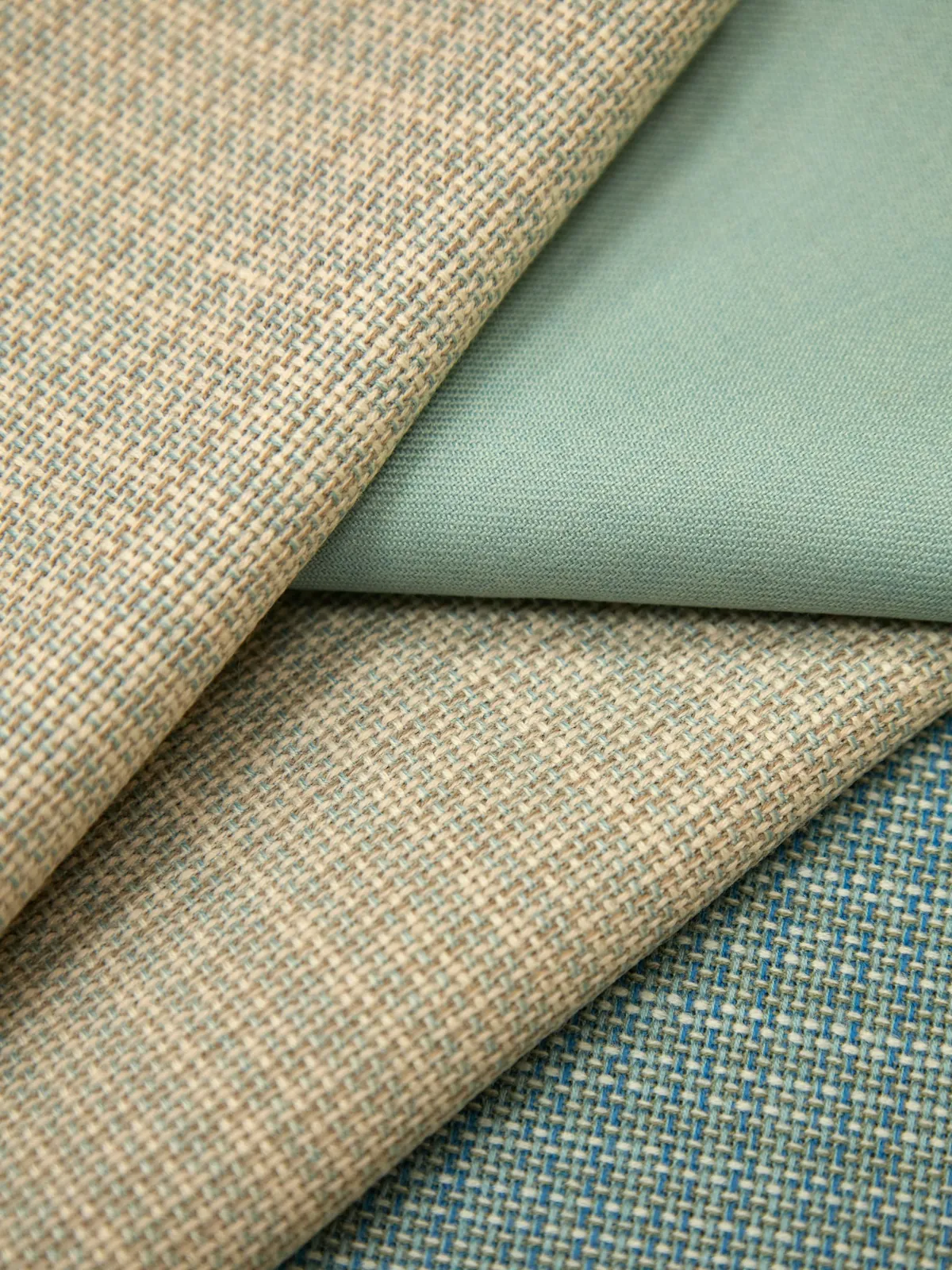 Folded woven fabrics in tan, sage green and blue