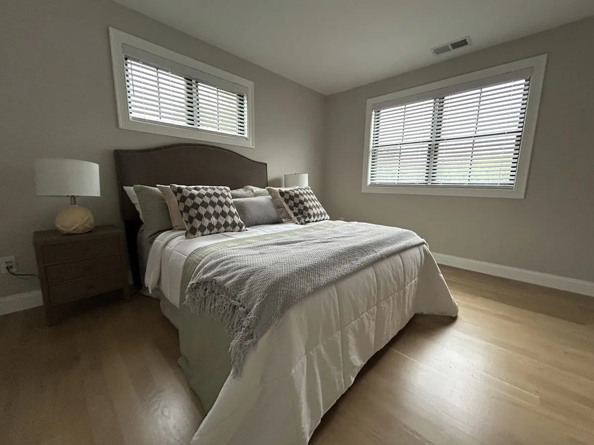 Bedroom with white plantation shutters on two windows