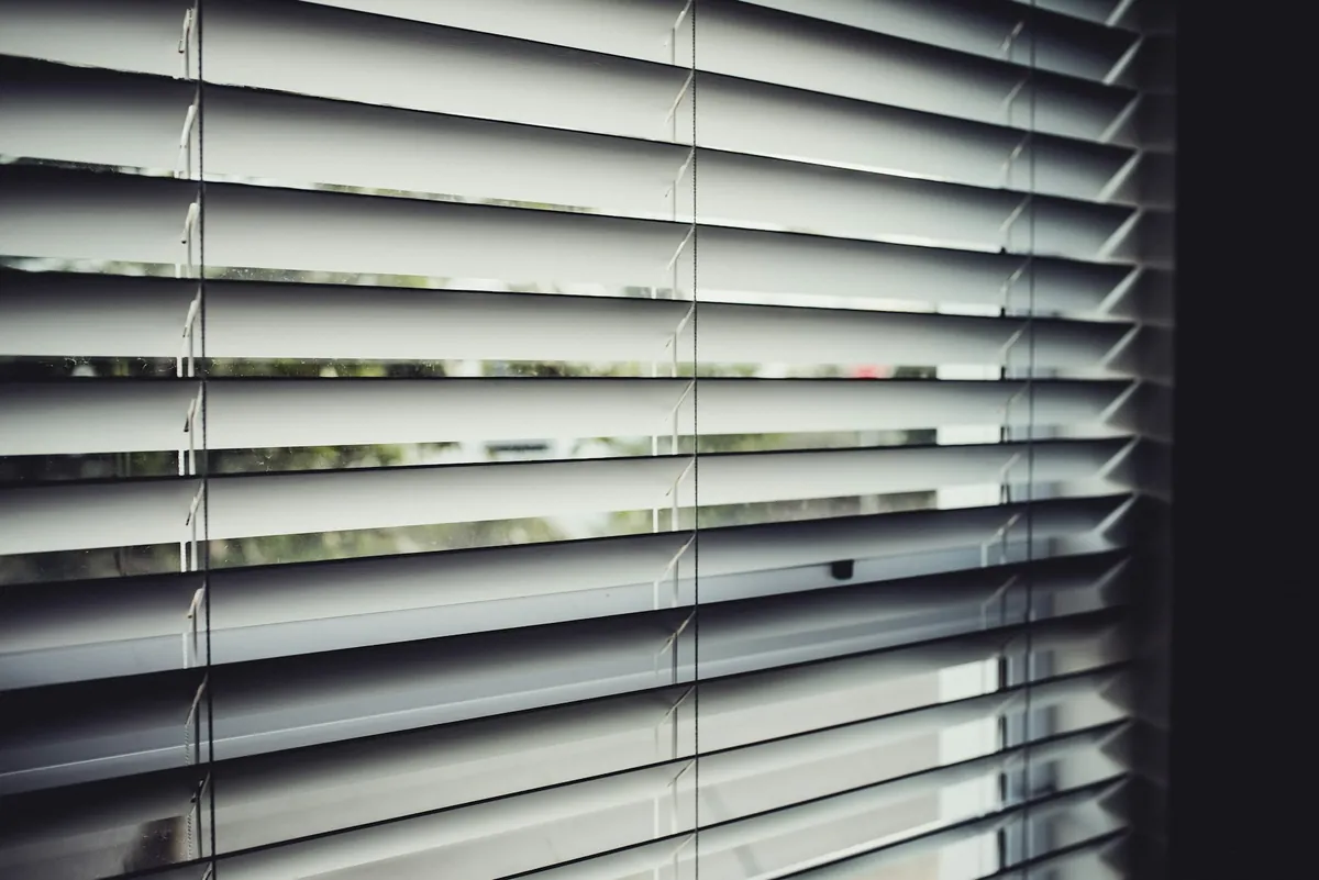 Close view of white horizontal blind slats with light between them