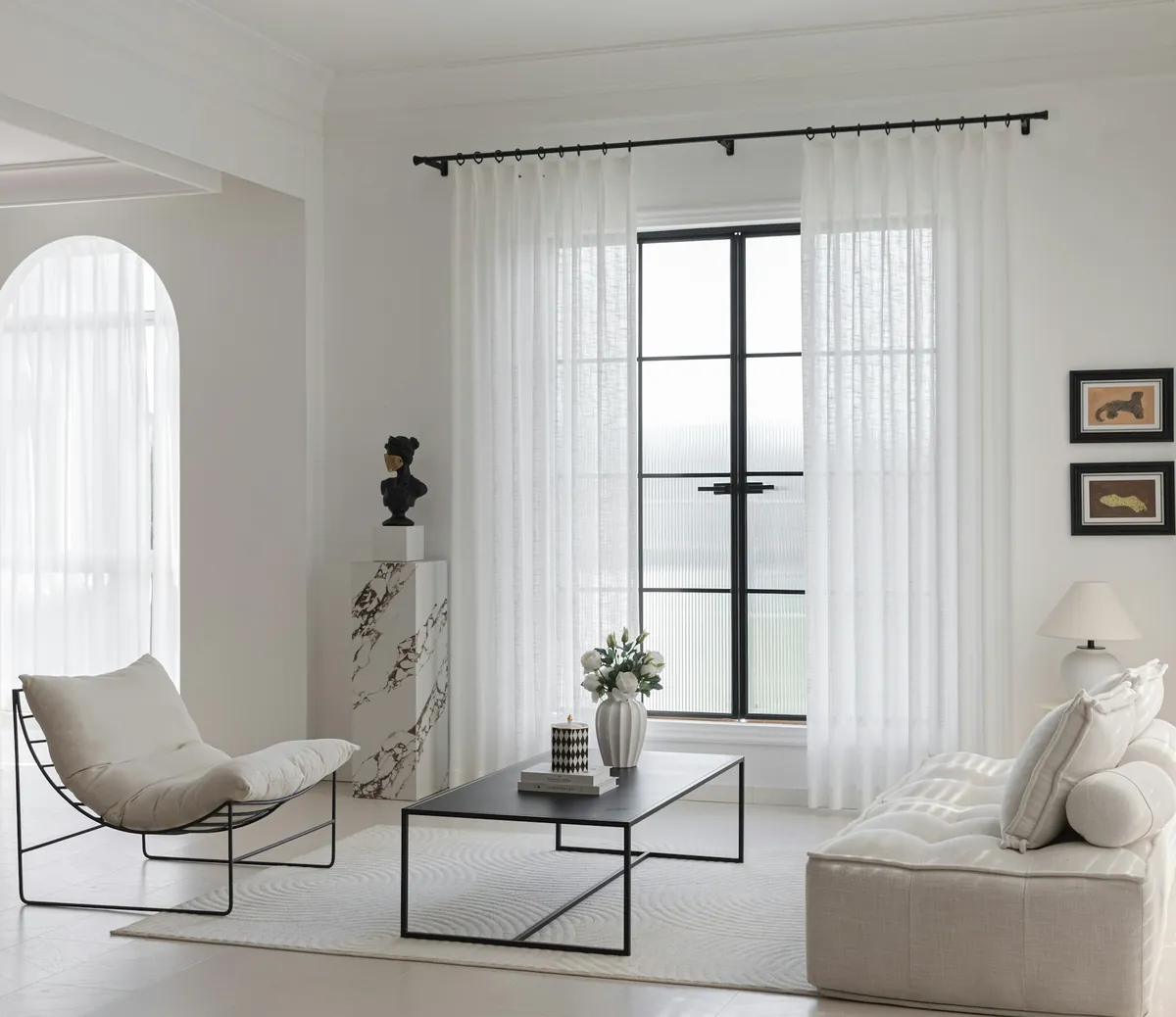 Sheer white curtains at tall windows in a pale living room