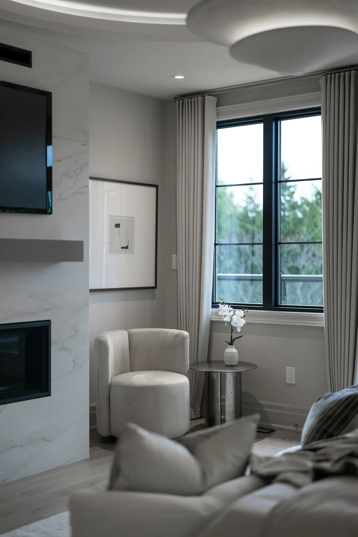 Living room with a fireplace and tall black-framed windows with sheer panels