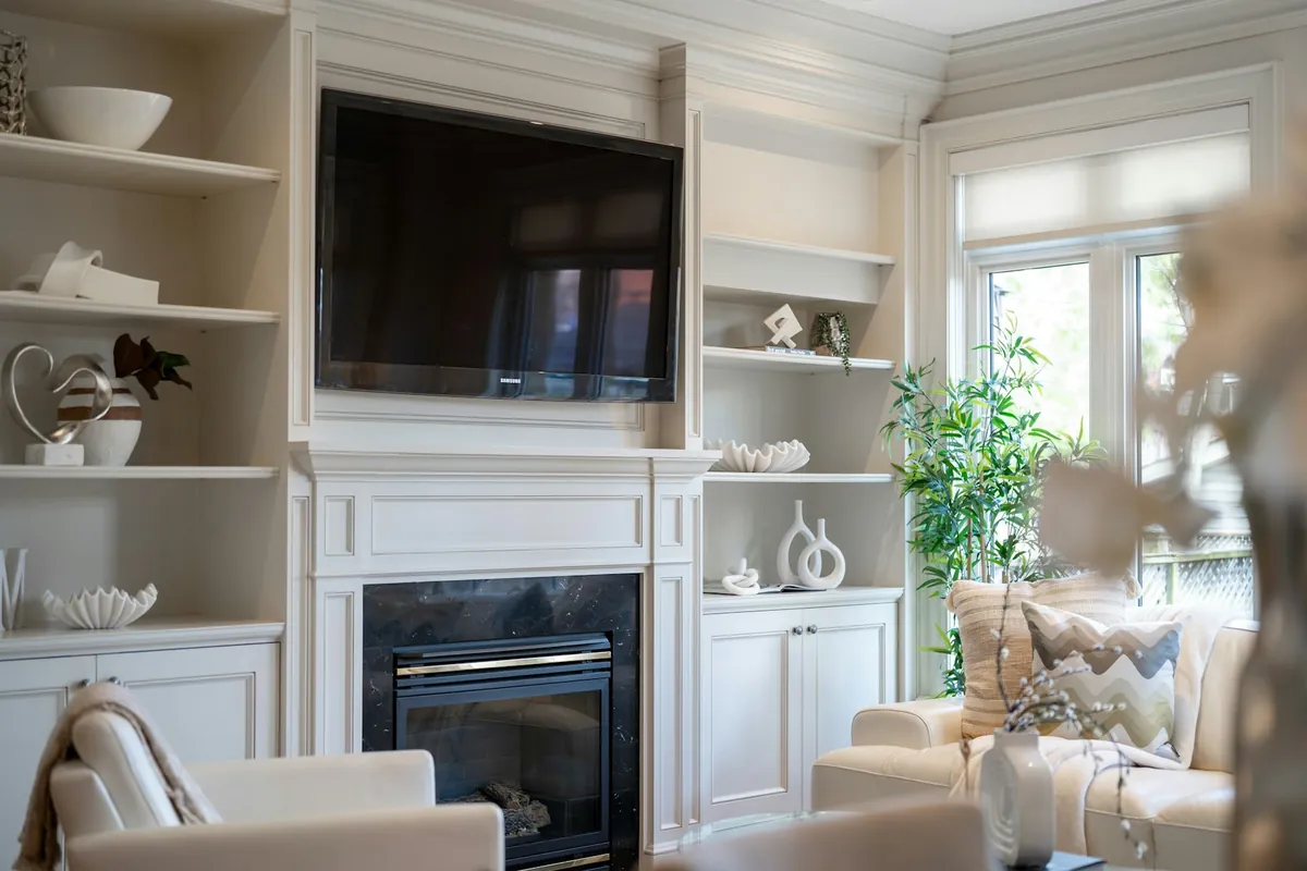 Family room with shades on the windows beside a fireplace and built-in shelves
