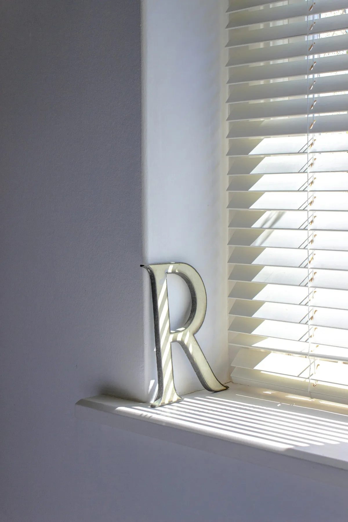 White horizontal blind beside a deep window sill