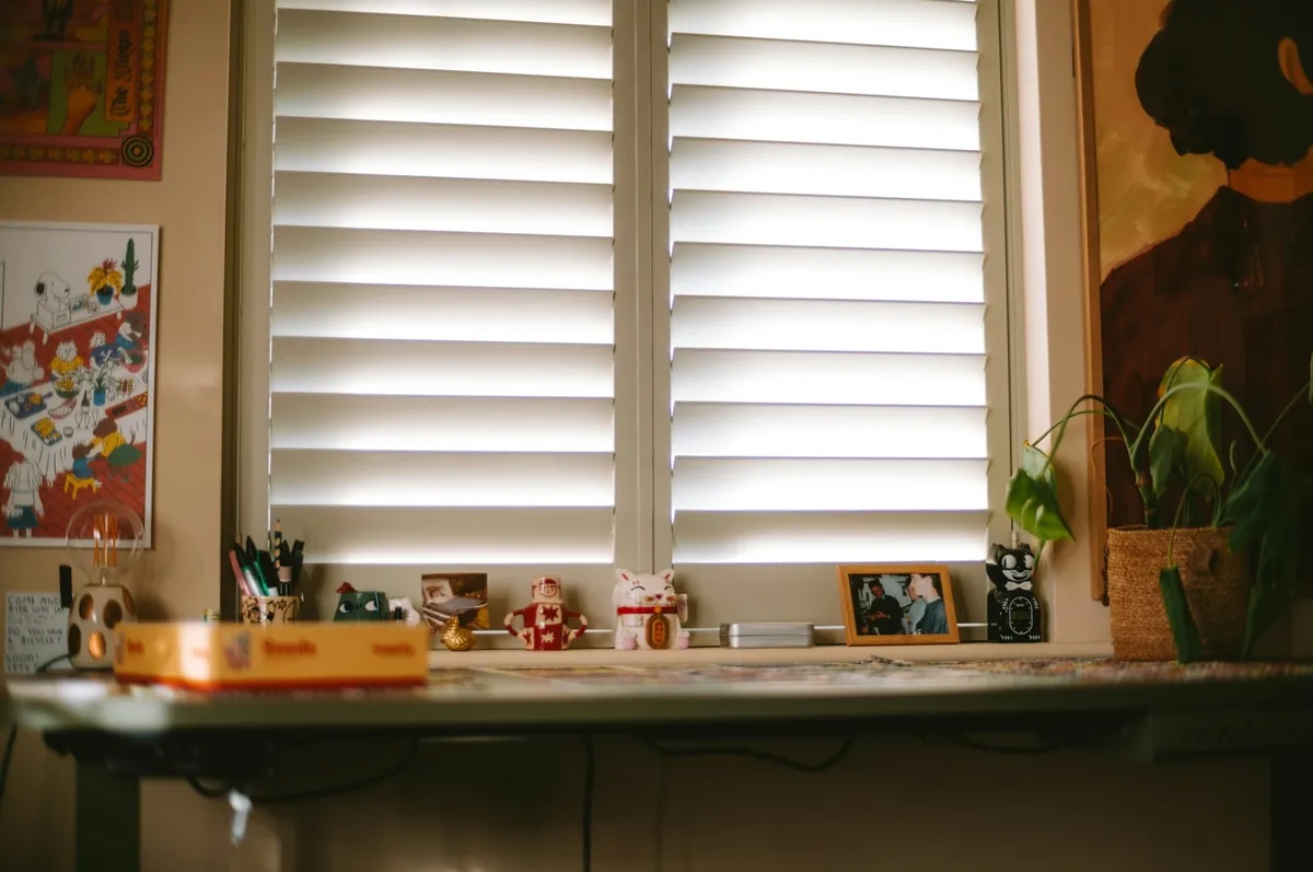 White plantation shutters on a window above a desk