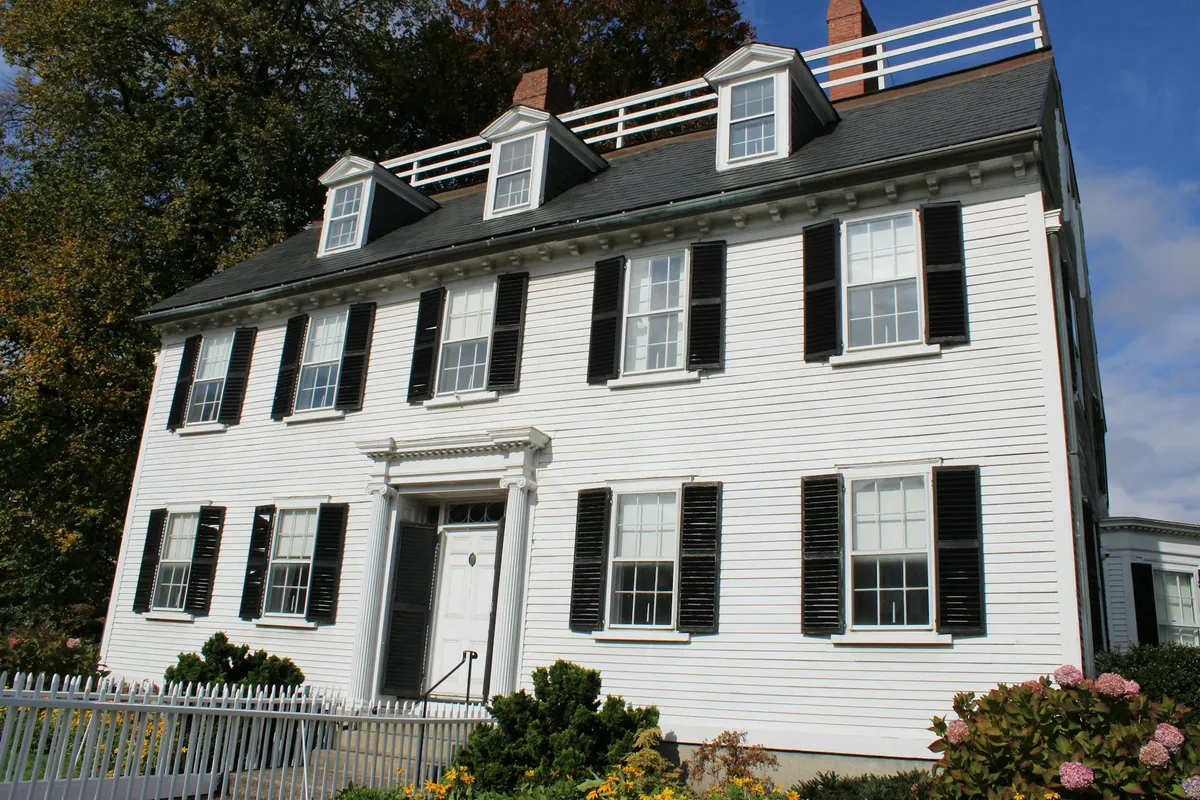 White Federal-style colonial with black shutters and a dormered roof
