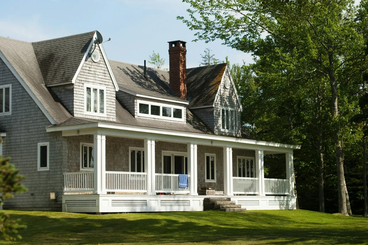 Shingled farmhouse with a deep white front porch and dormers