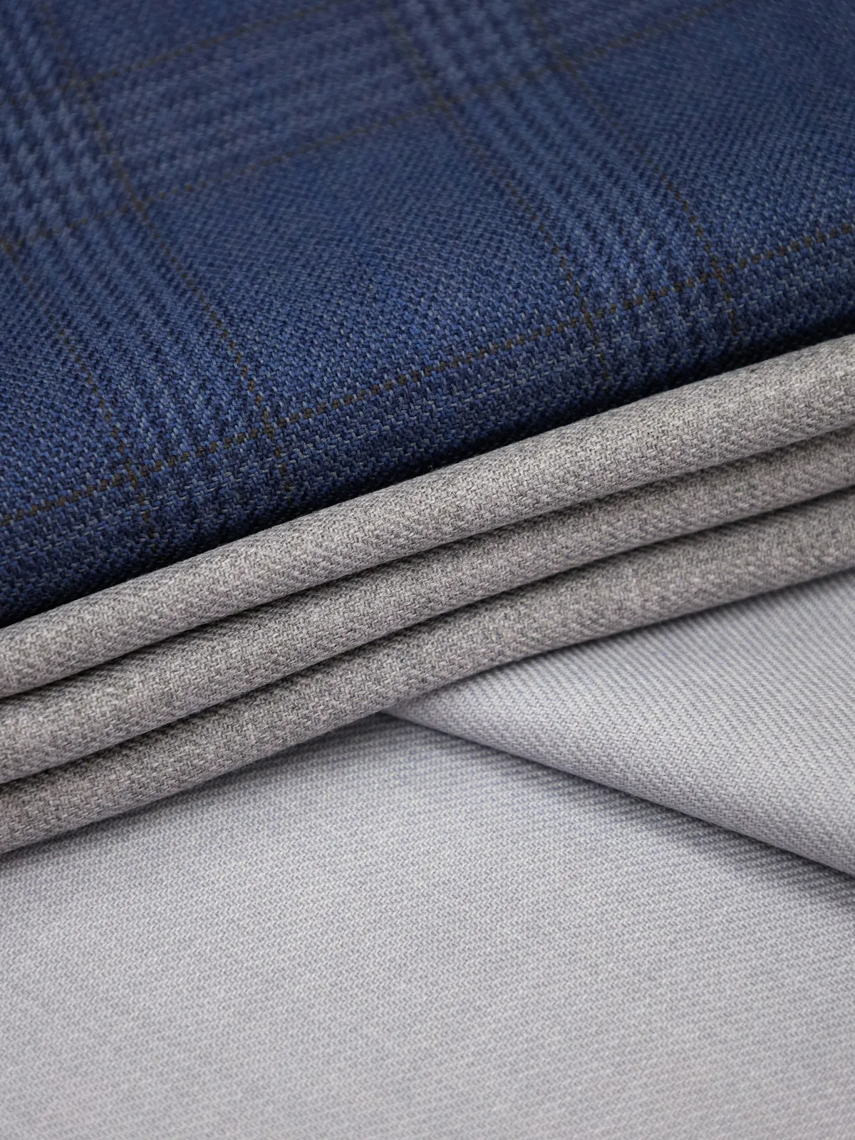 Navy plaid and grey woven fabrics folded together