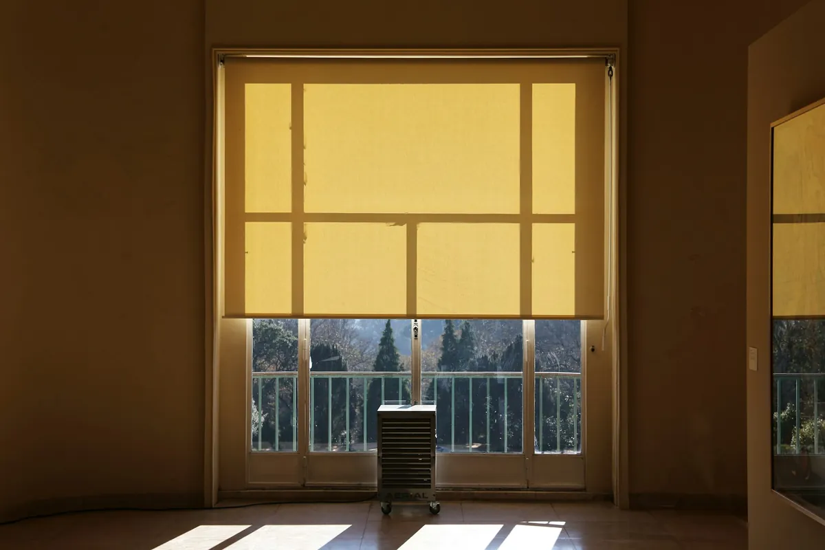 Yellow roller shade pulled halfway down a tall window