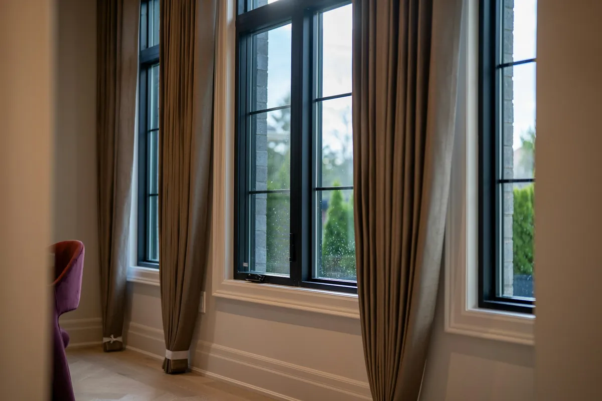 Taupe drapery panels framing tall black-framed windows