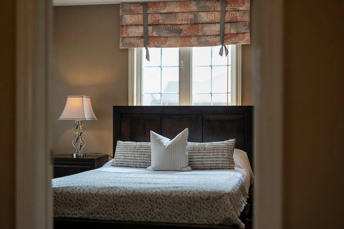 Bedroom with a fabric valance above the window and a dark headboard