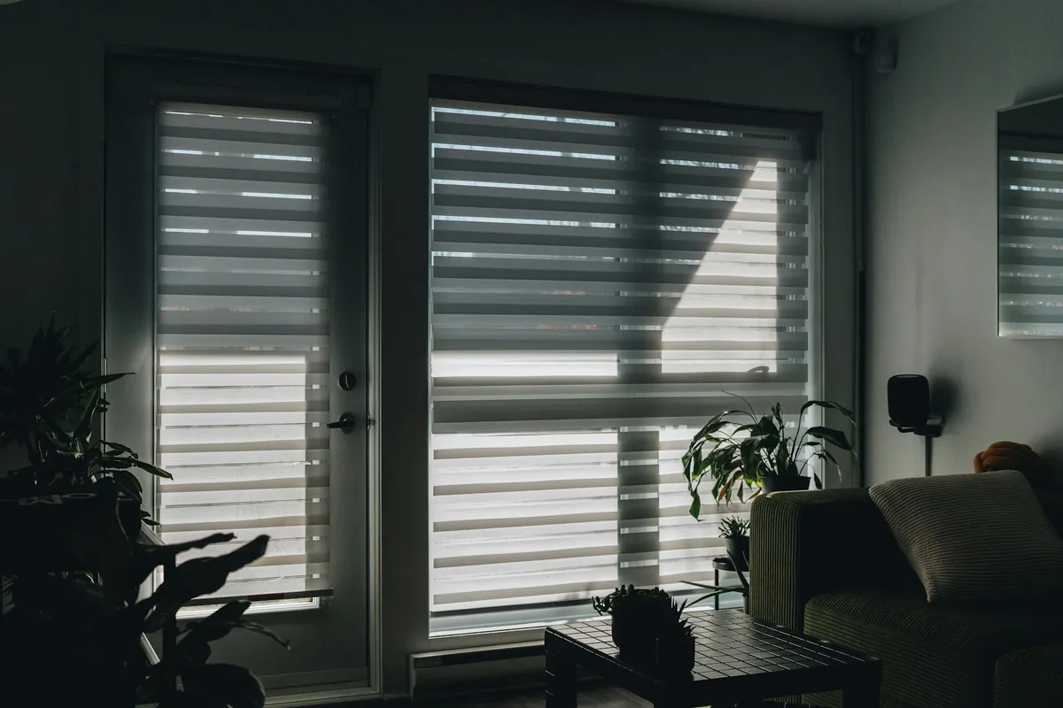 Dual sheer shades on glass doors in a dim living room