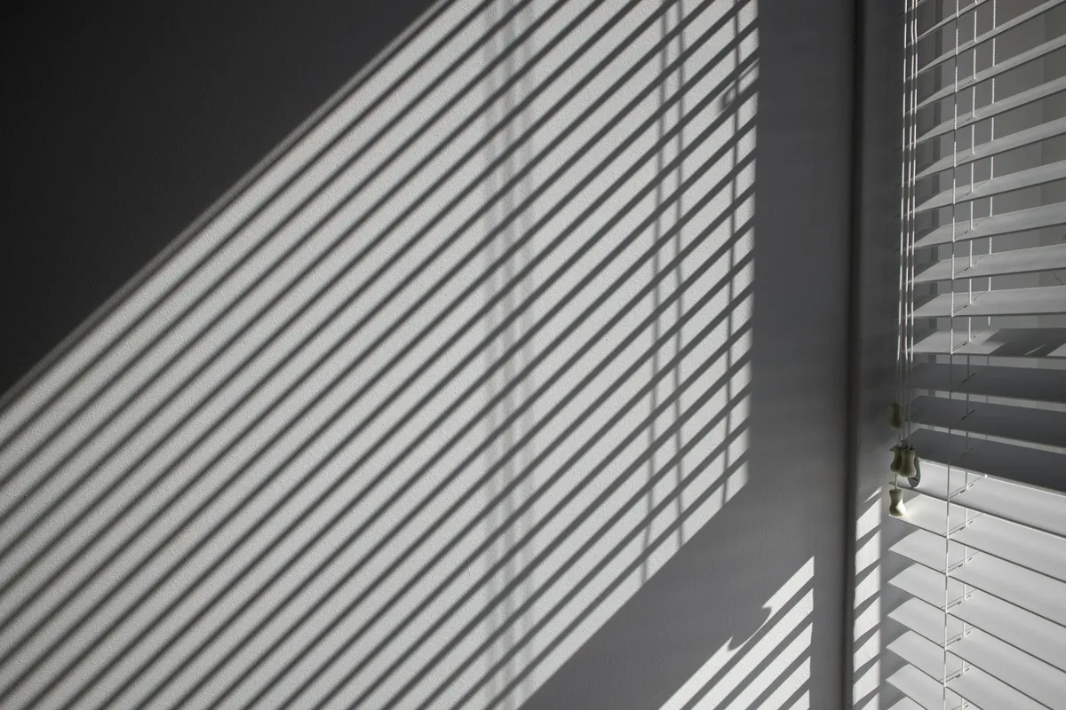 Light through horizontal blinds casting stripes on a wall