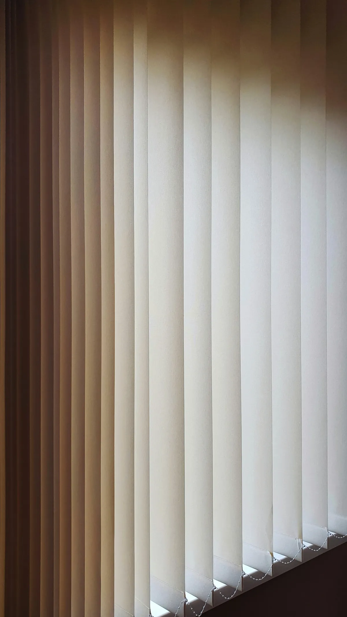 Pale vertical blinds hanging at a tall window