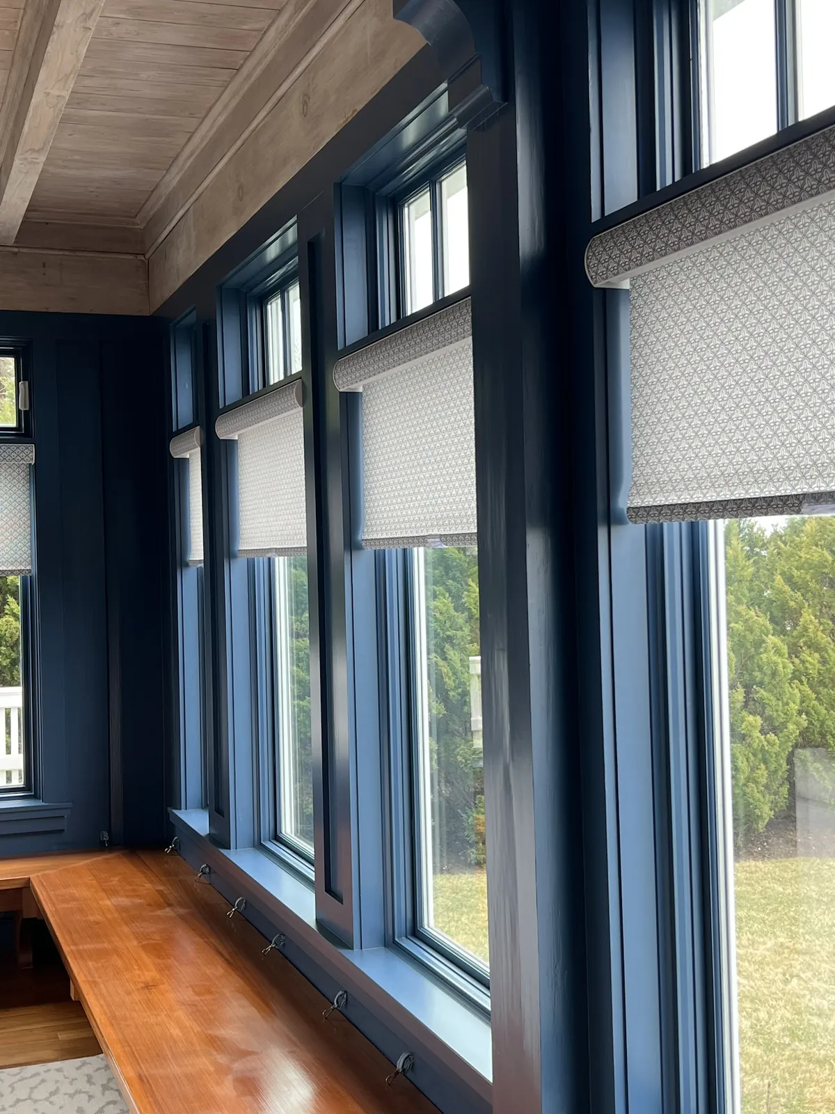 Close view of roller shades on navy-framed sunroom windows
